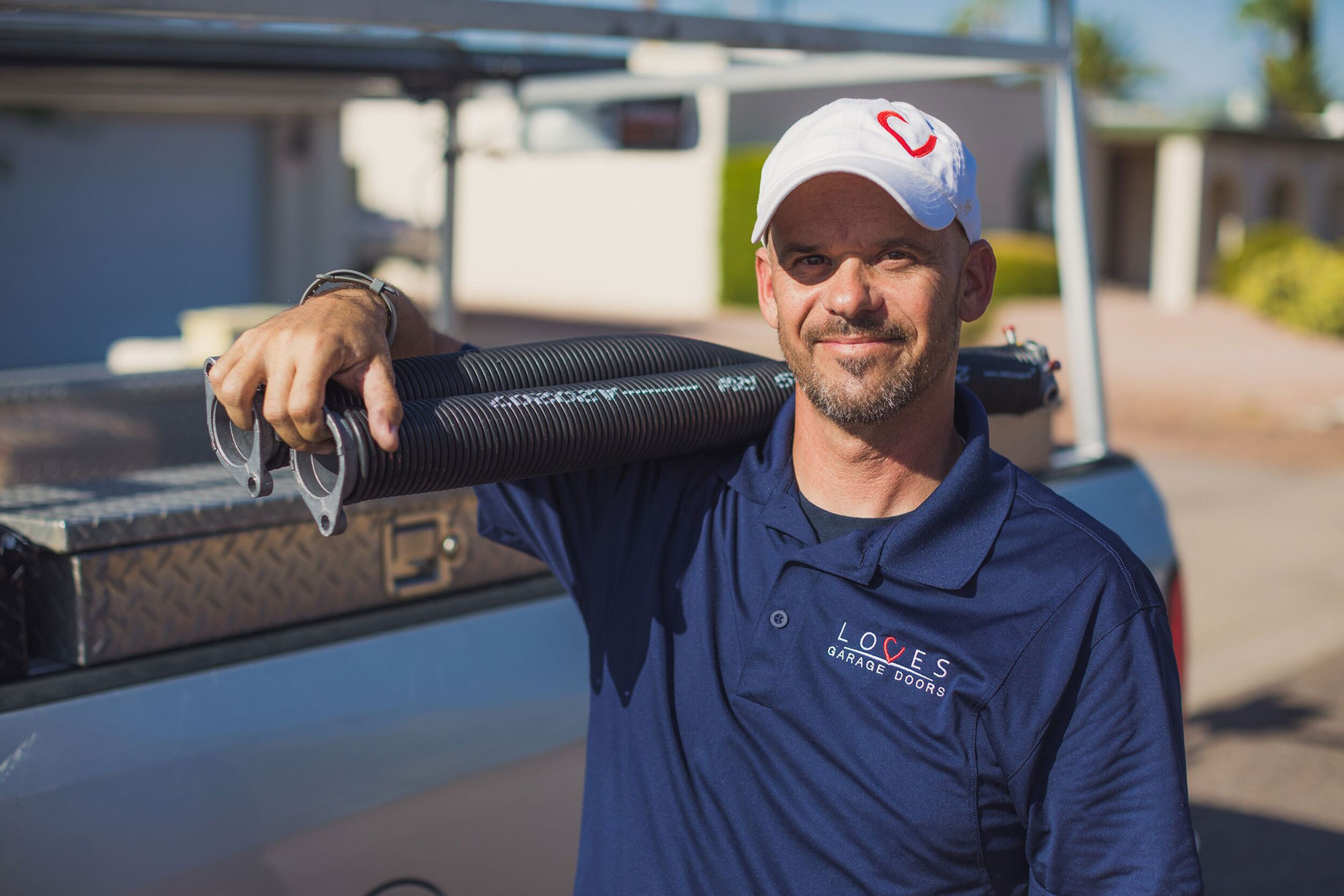 Professional technician from Loves Garage Doors holding springs, ready for installation work outdoors.