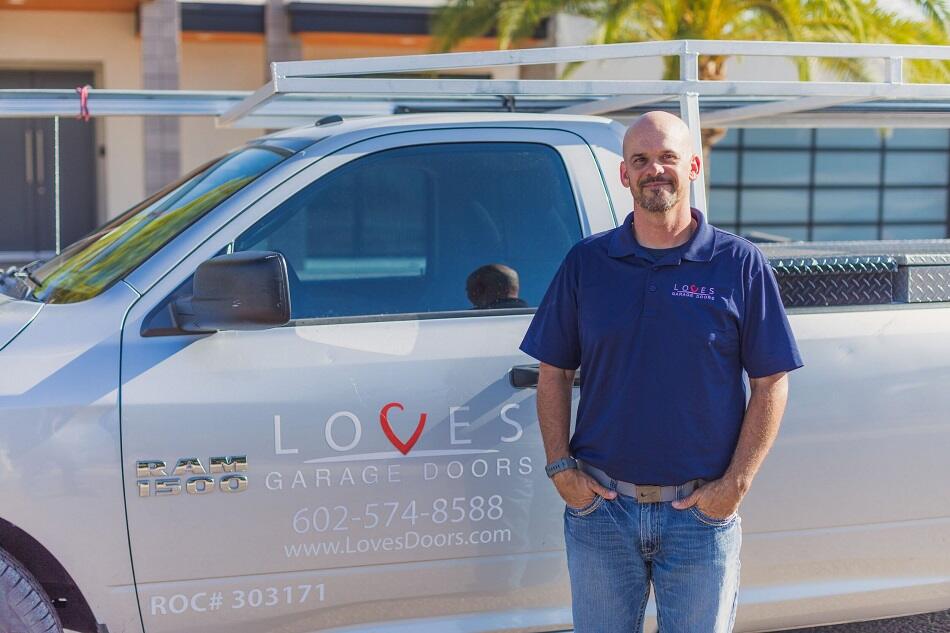 A technician from Love's Garage Doors stands proudly beside a branded service truck, ready to assist customers.