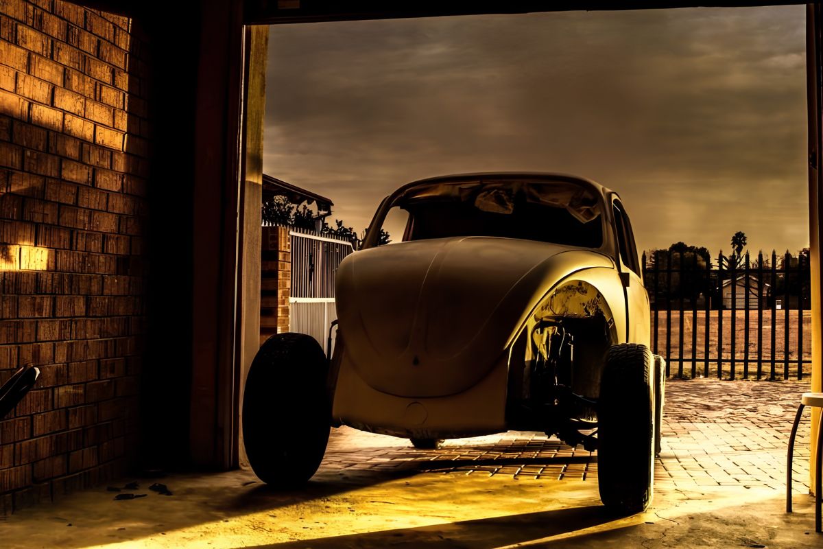 A vintage car project sits inside a garage with its door open, highlighting the need for regular garage door maintenance.