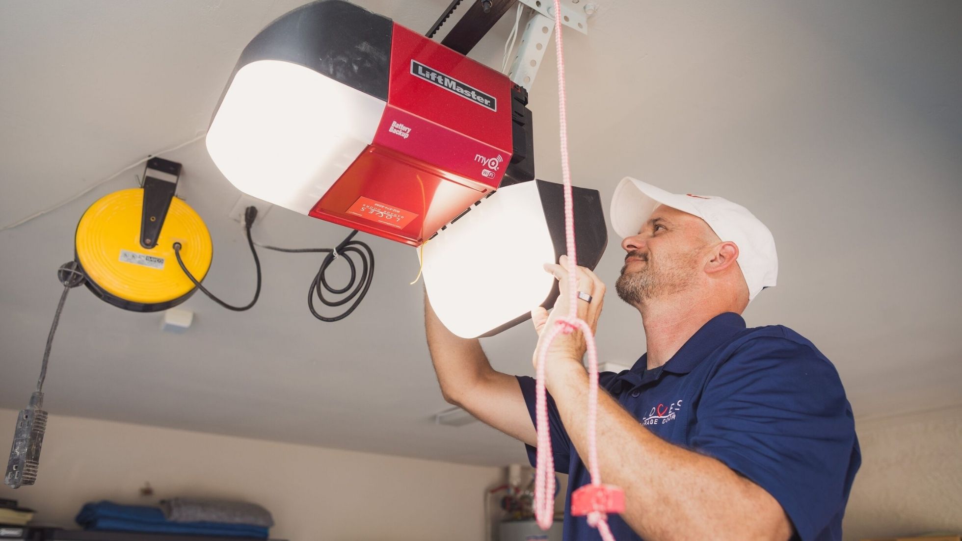 A technician installs a LiftMaster garage door opener while working in a well-lit garage setting.